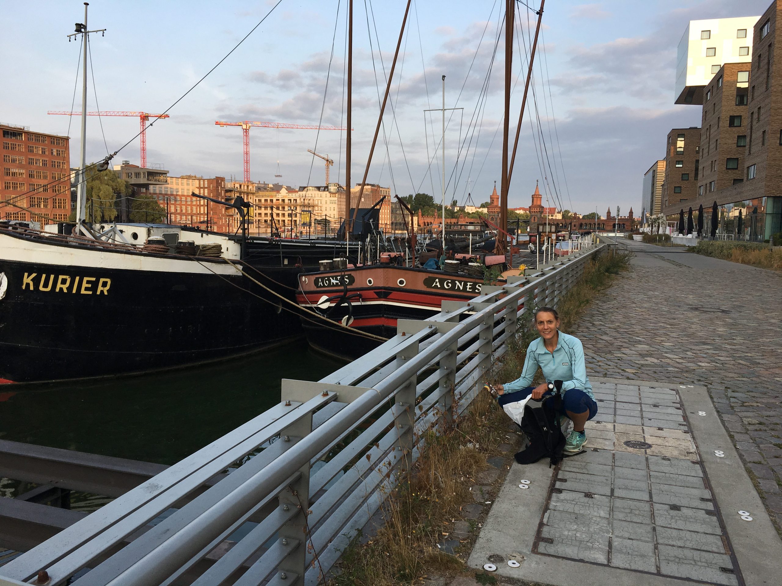 Frau sammelt an der Spree Müll ein.