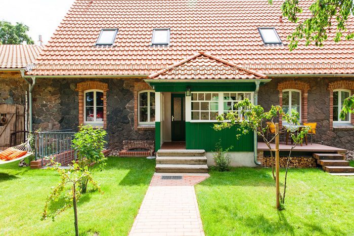 Das Haus von außen bei Sonnenschein und grünem Rasen.