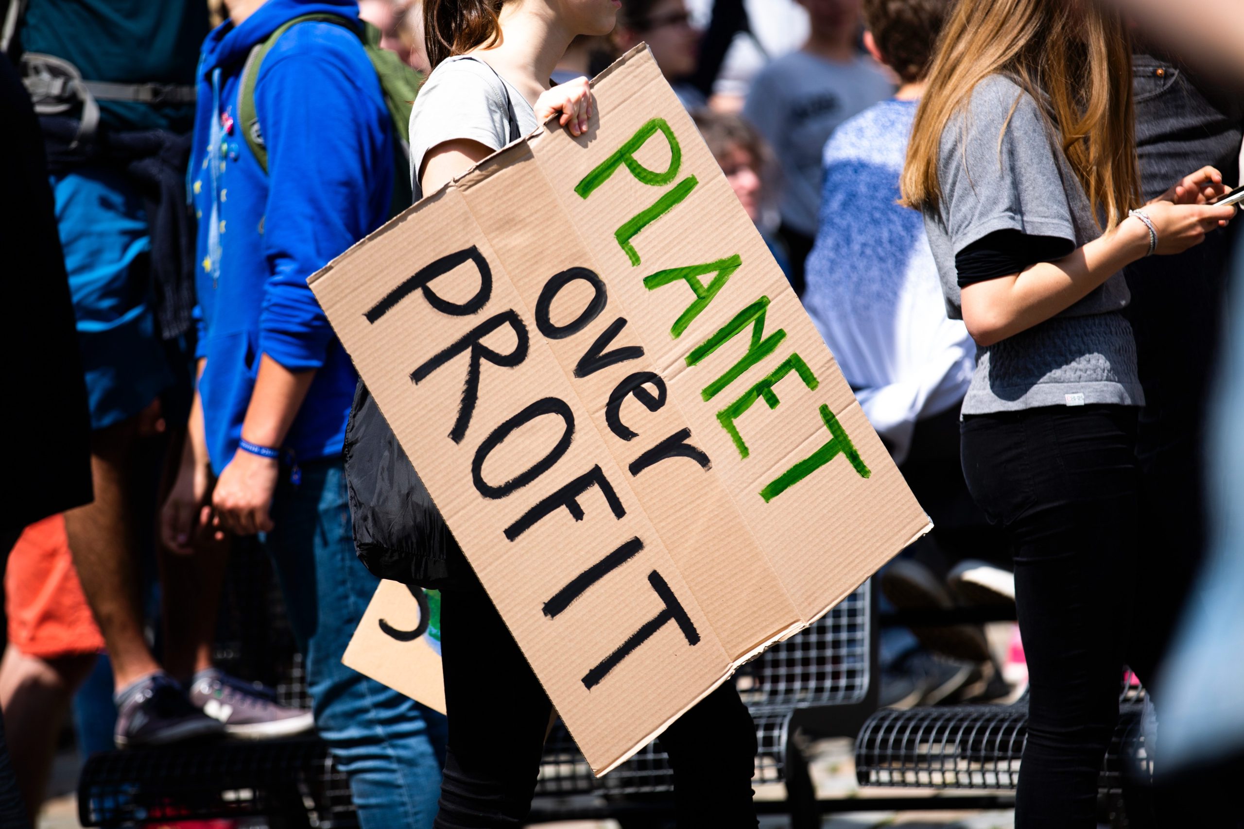 Eine Demonstration, eine Frau trägt ein großes Pappschild mit der Aufschrift: Planet over Profit.