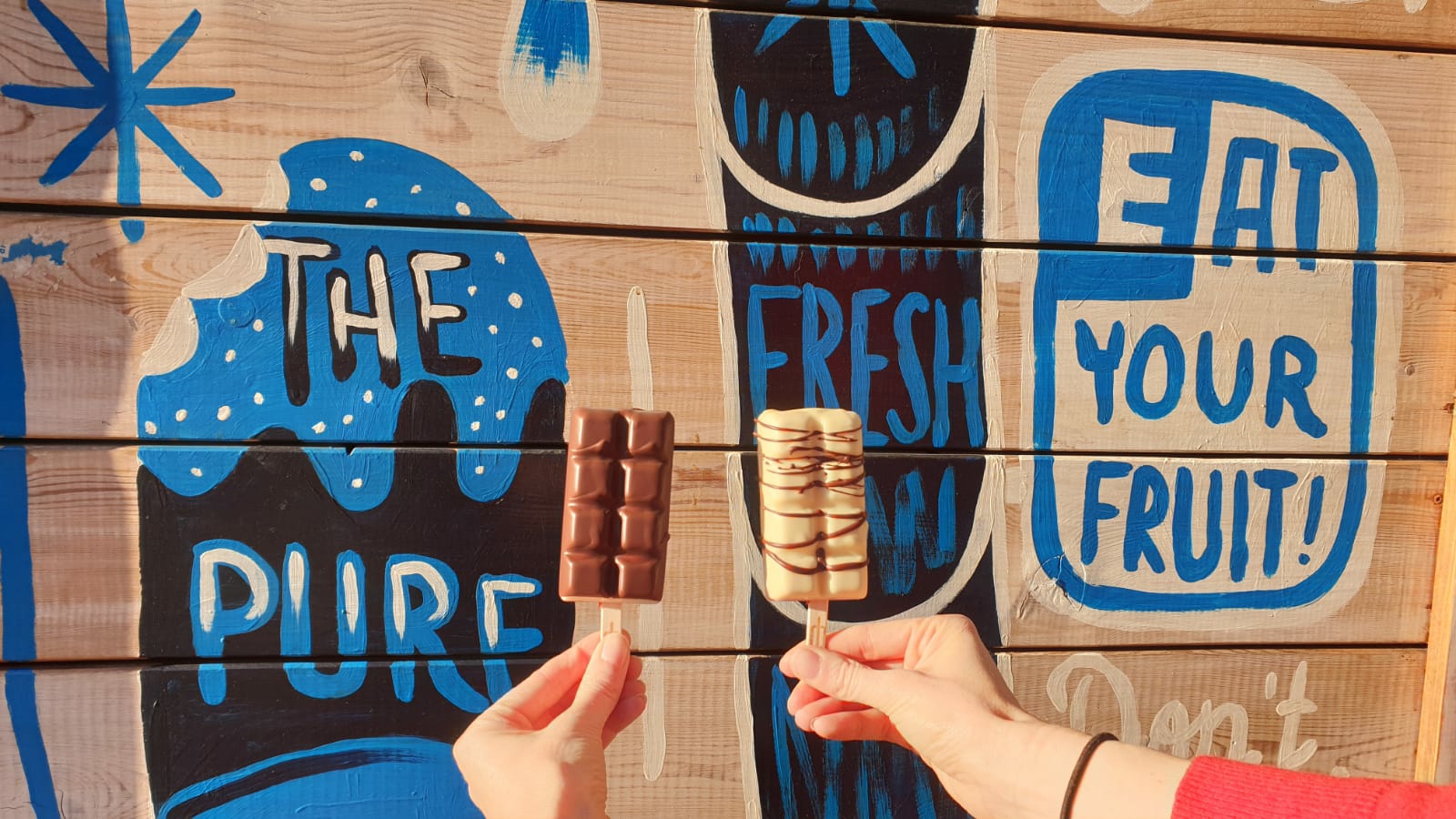 Zwei Eis am Stiel vor bemalter Holzwand