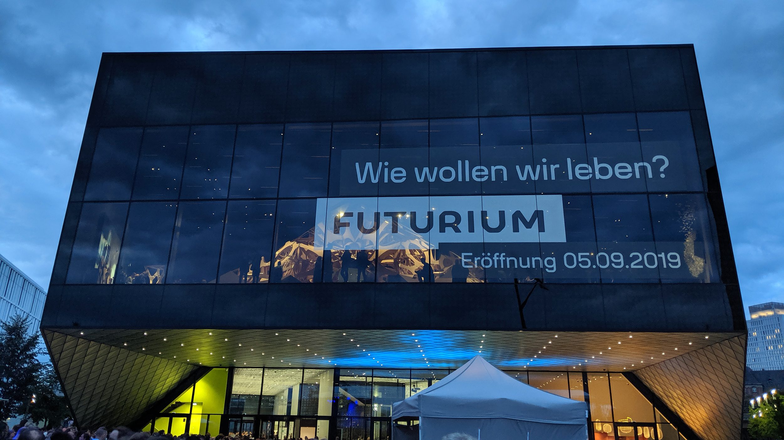 Rechteckiger, futuristischer Bau des Futurium in Berlin, darüber wolkiger Abendhimmel