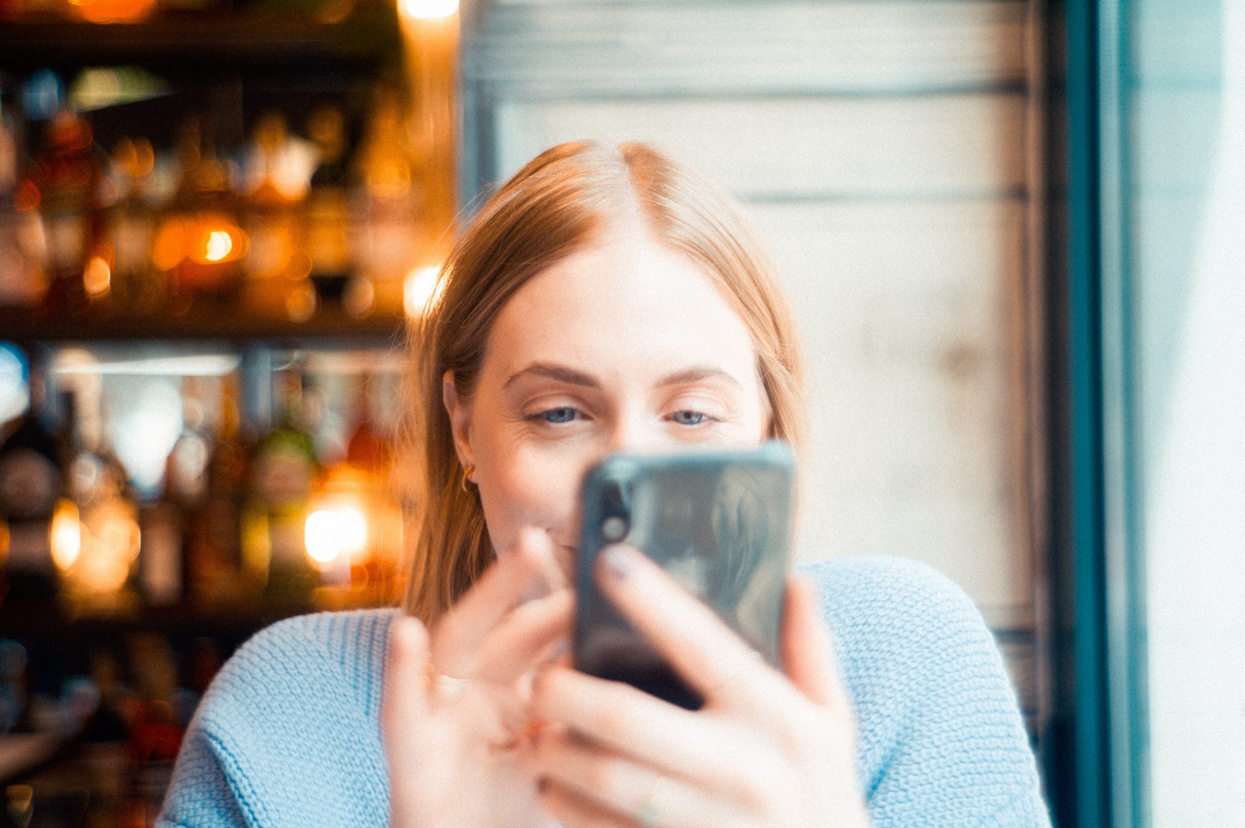Frau mit Handy allein am Tisch