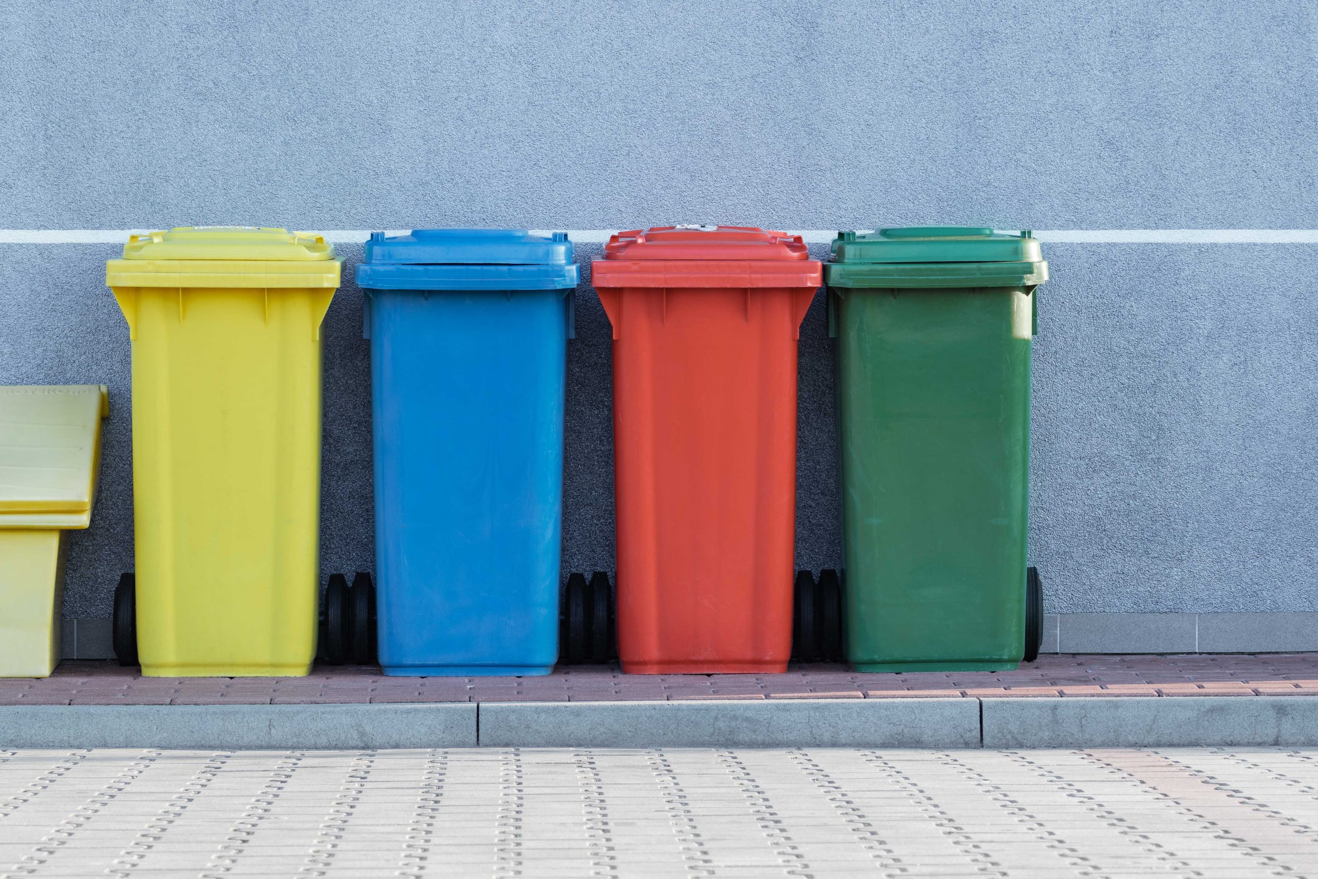 Gelbe, blaue, rote und grüne Mülltonne nebeneinander.