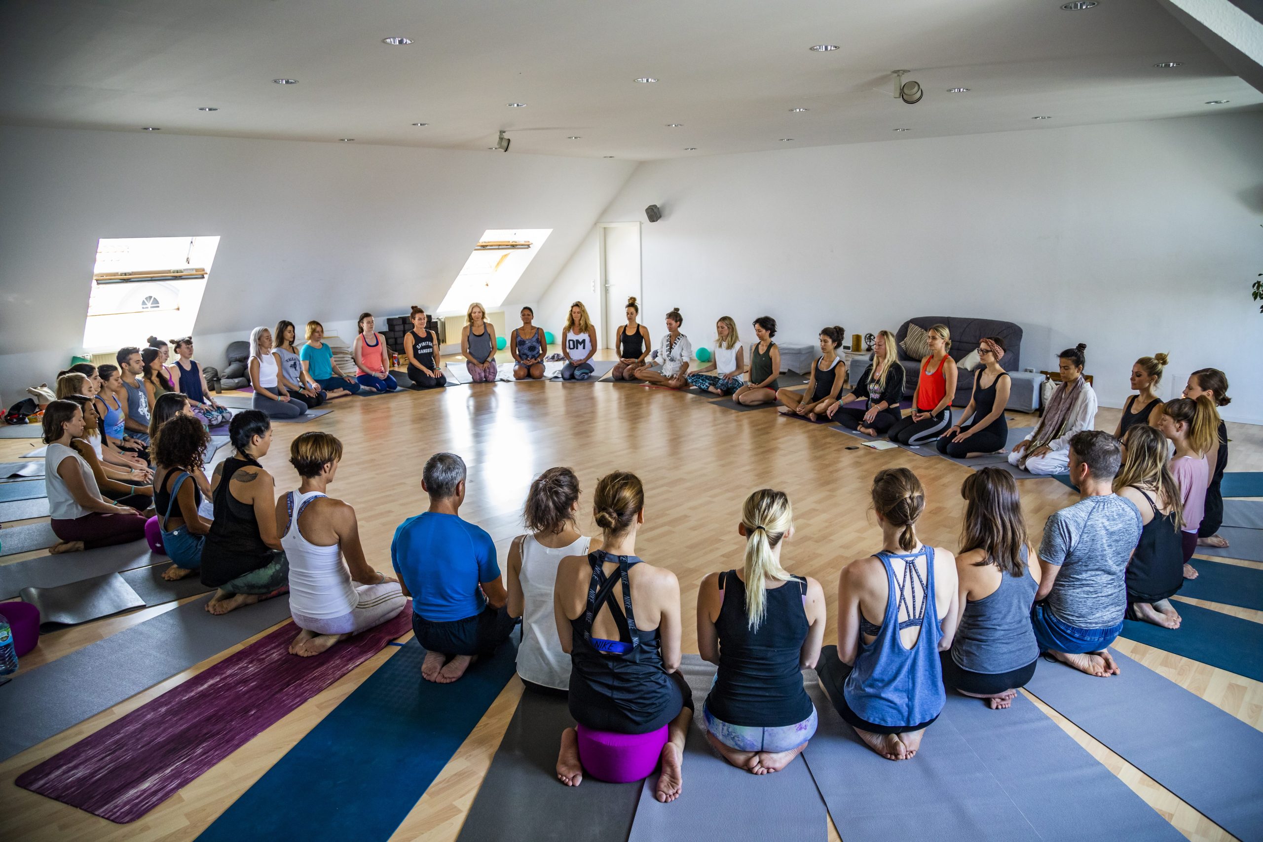 Menschen sitzen auf Yogamatten in einem Kreis.